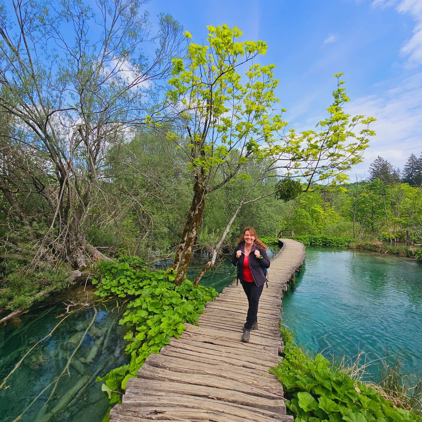 Eine Frau überquert eine Holzbrücke über klares Wasser, ein Symbol für mutige Schritte in die Veränderung.
