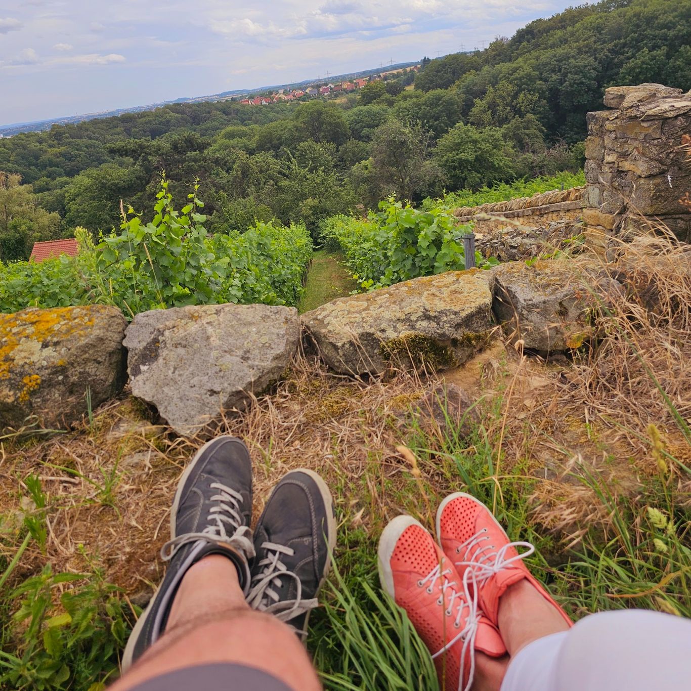  Zwei Menschen sitzen entspannt auf einem Felsen mit weitem Blick in die Natur – ein Moment des Innehaltens und Vergleichens.