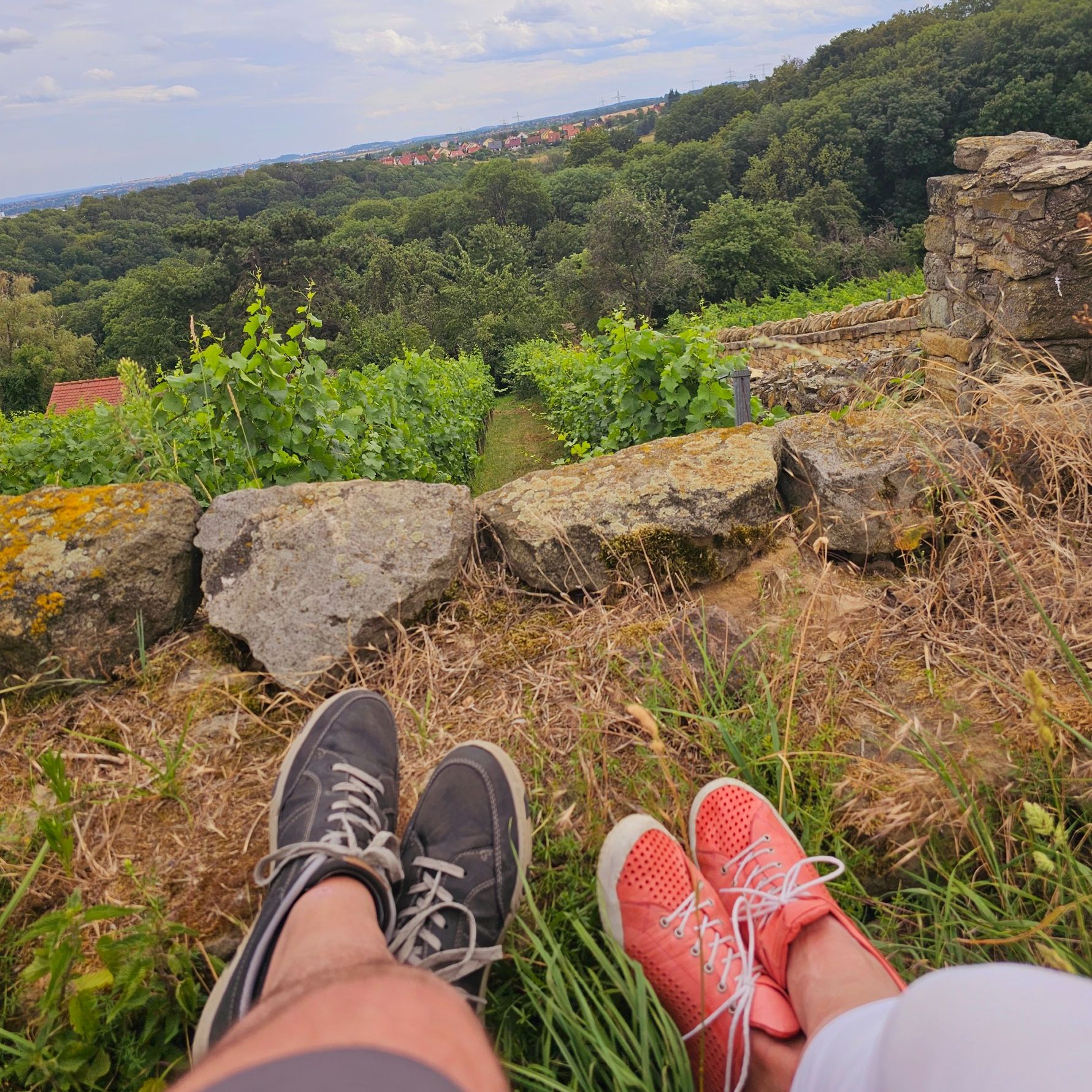  Zwei Menschen sitzen entspannt auf einem Felsen mit weitem Blick in die Natur – ein Moment des Innehaltens und Vergleichens.